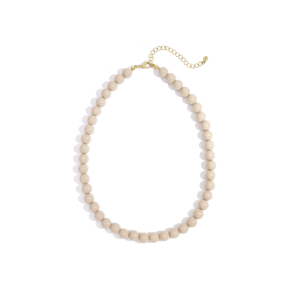 Beige kralenketting met ronde kralen en goudkleurige sluiting op witte achtergrond