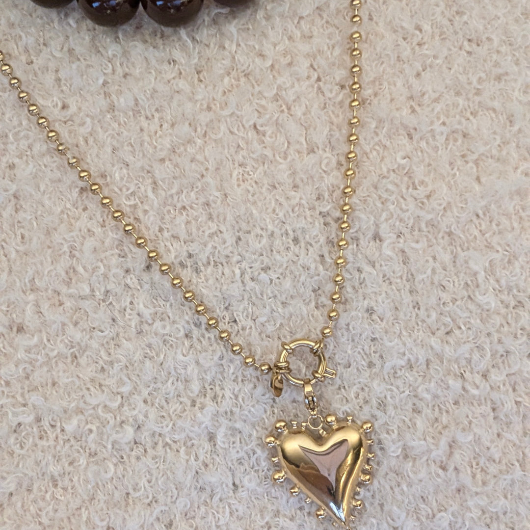 beige trui met balletjes ketting met statement hart