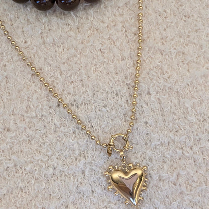 beige trui met balletjes ketting met statement hart