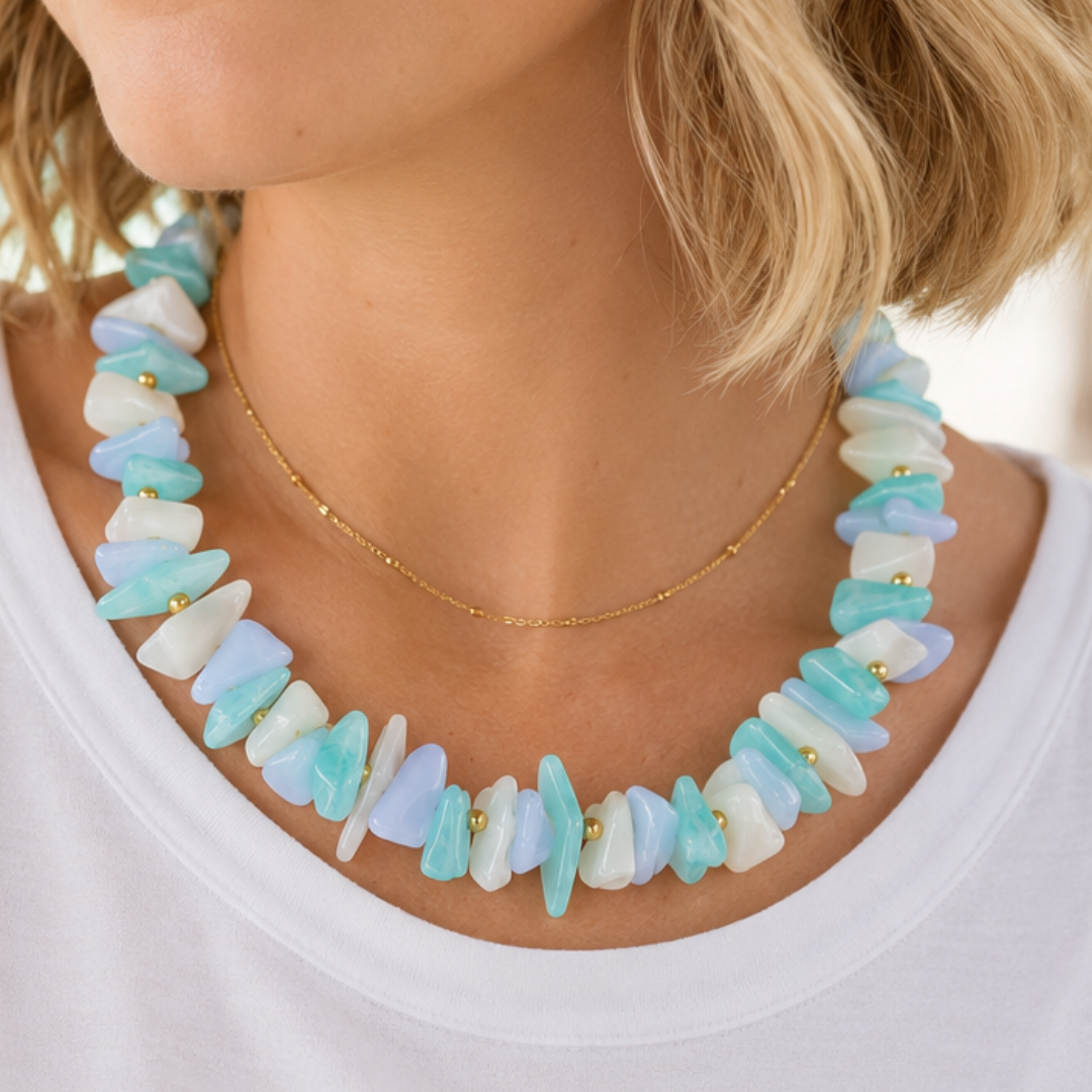 model met Blauw-witte schelpen kralenketting met lichtblauwe, turquoise en witte organische kralen, goudkleurige details en verstelbare sluiting van Casa Jadel.