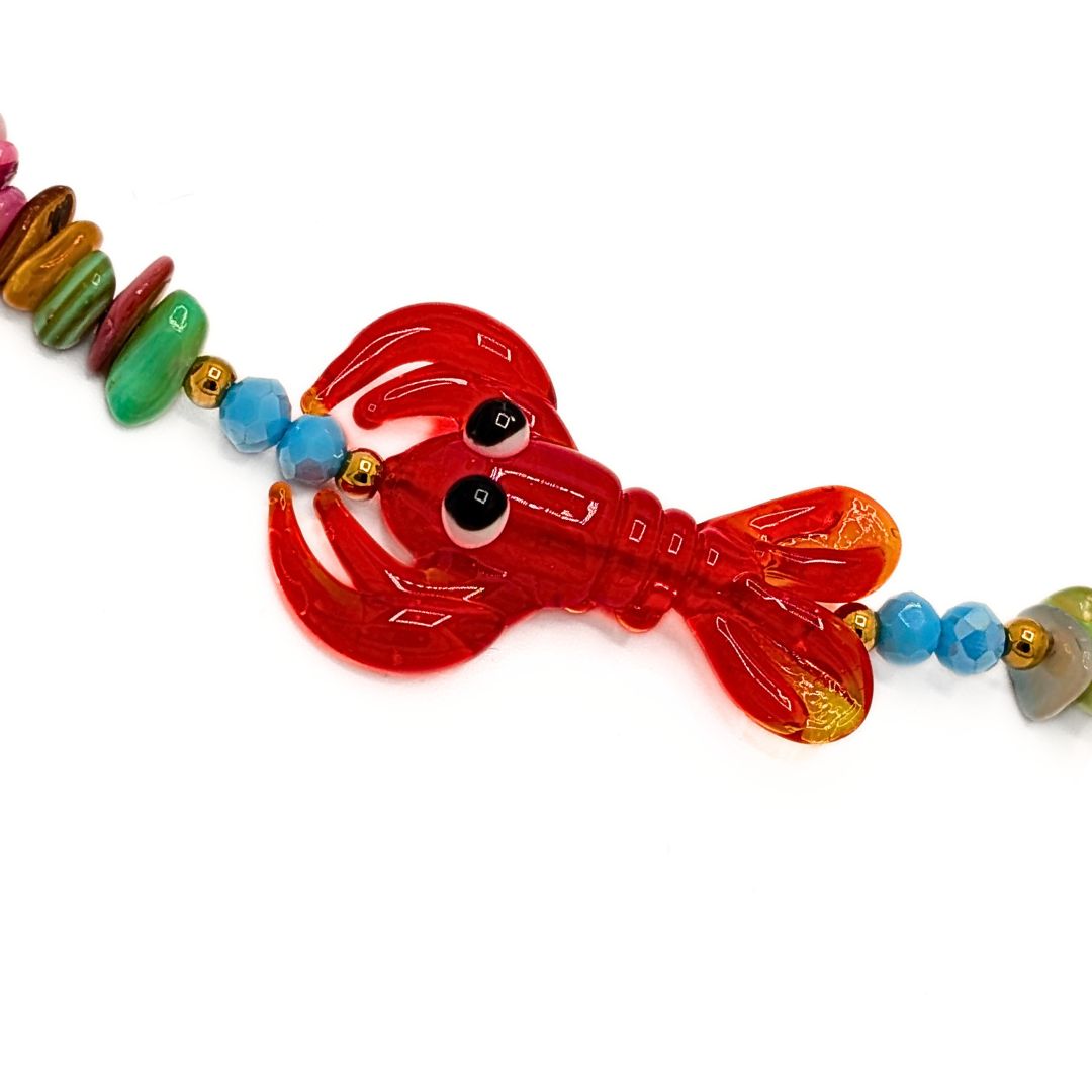 rode kreeft bedel aan kleurrijke schelpen kralenketting met turquoise kralen en goudkleurige details