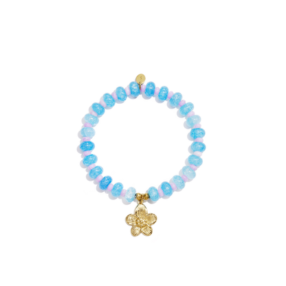Blauwe glazen kralenarmband met lila tussenkralen en goudkleurige bloem bedel op witte achtergrond.
