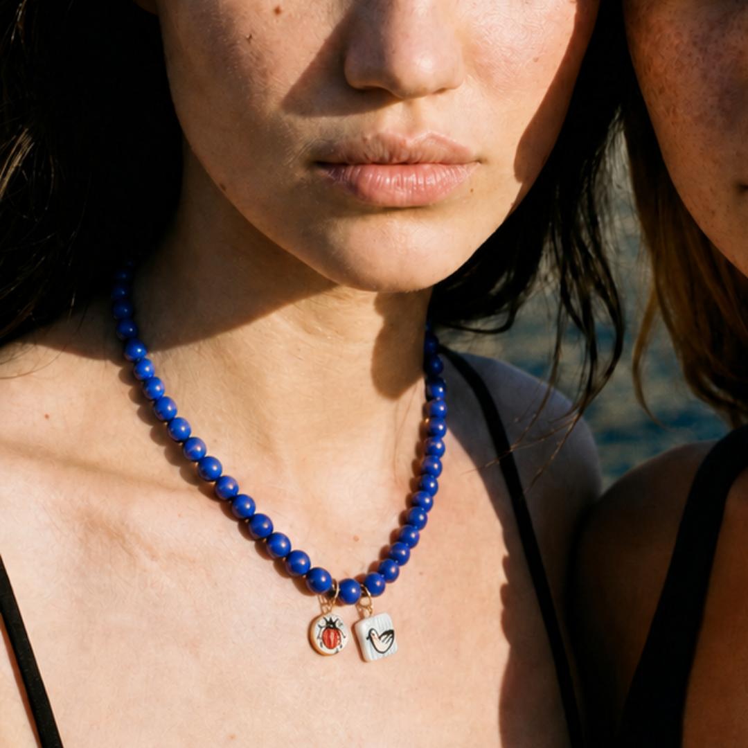 Model draagt blauwe kralenketting met kleine bedels van Casa Jadel