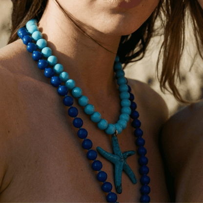Model draagt blauwe kralenketting met grote zeester hanger van Casa Jadel