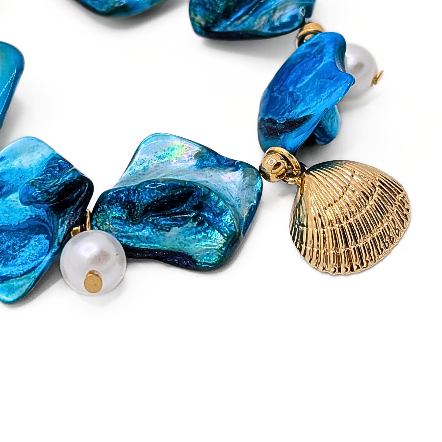 Detail blauwe schelpen armband met gouden schelp bedel en parel