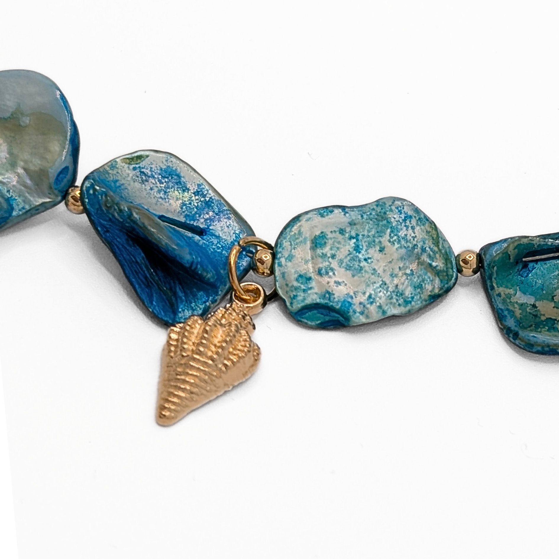 Detail blauwe schelpen ketting met gouden schelp bedel