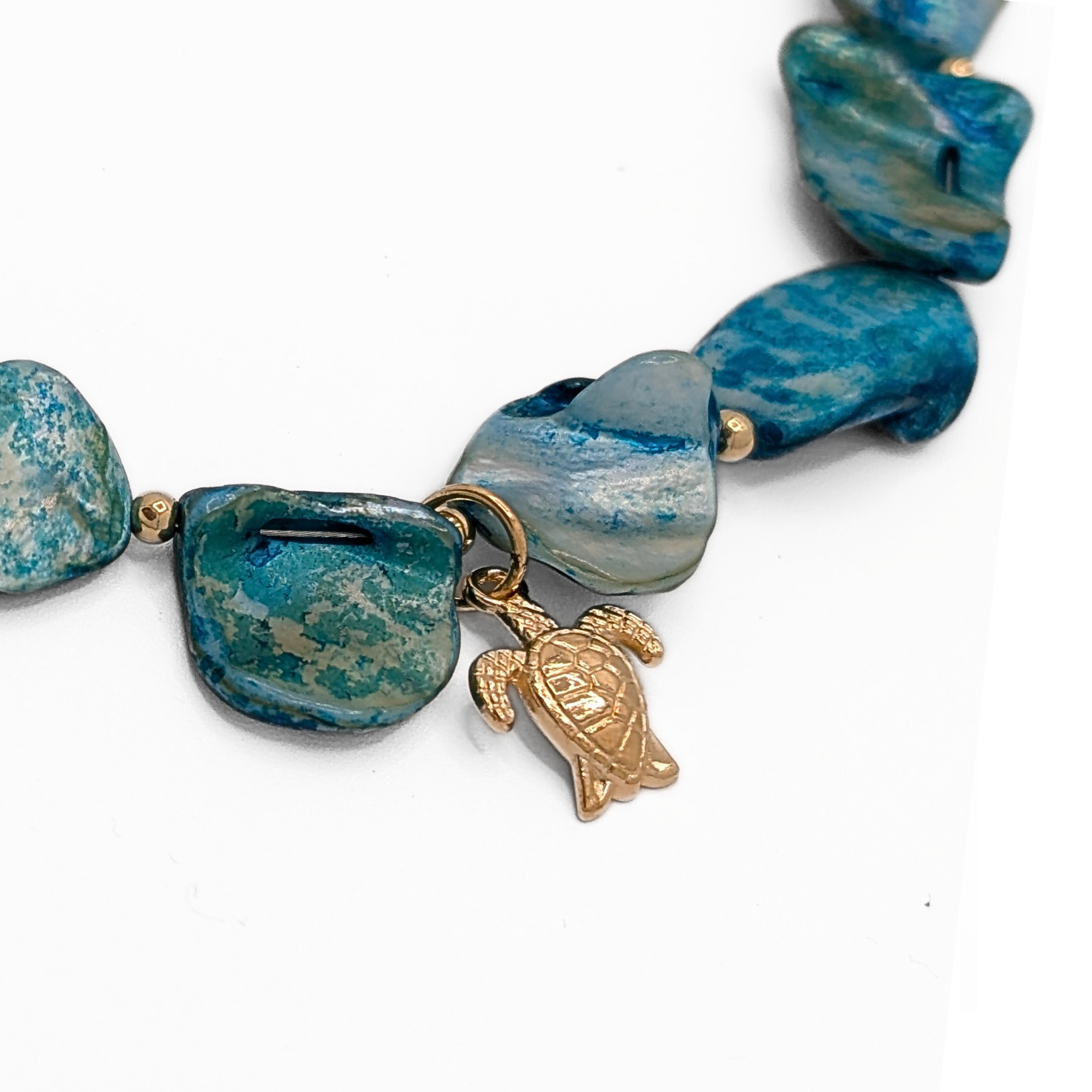 Detail blauwe schelpen ketting met gouden zeeschildpad bedel