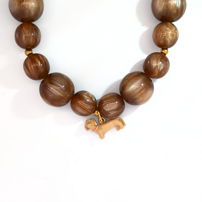 Blonde teckel hond bedel gedragen aan een groene kralenketting met goudkleurige sluiting

