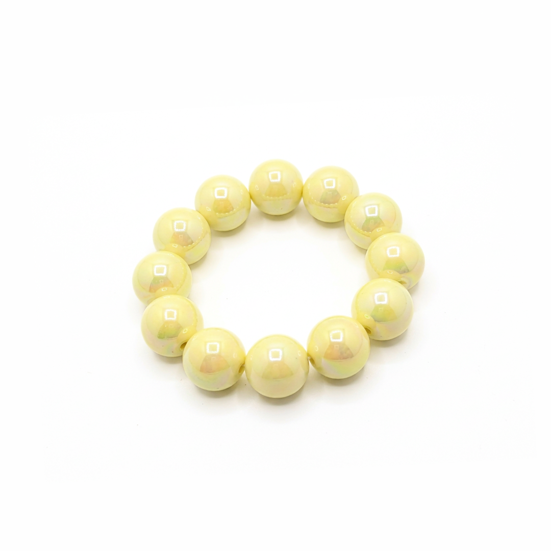 botergele chunky kralenarmband met grote glanzende kralen op lichte achtergrond schuin.