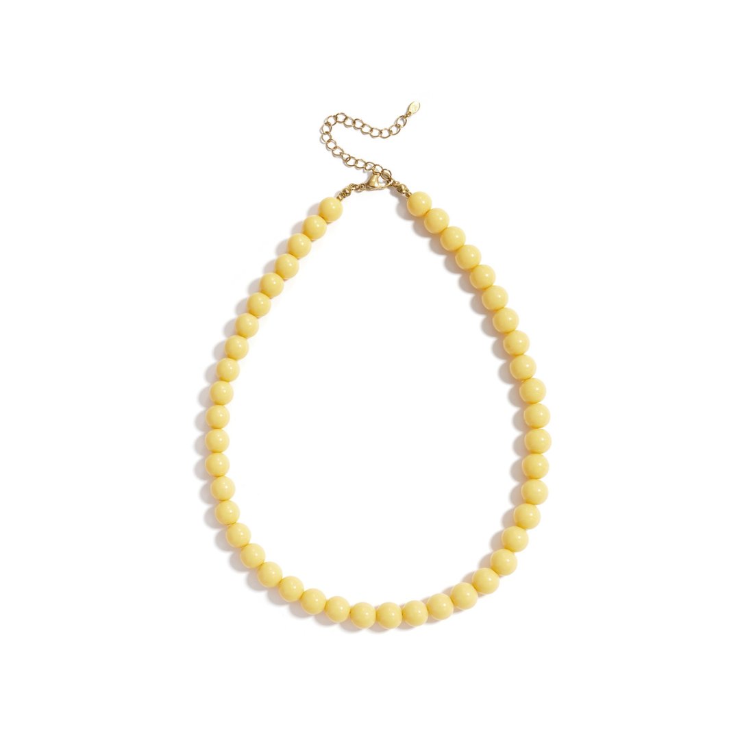 Botergele kralenketting met ronde glanzende kralen en goudkleurige sluiting op witte achtergrond