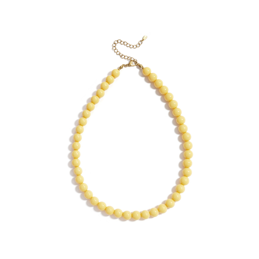 Botergele kralenketting met ronde glanzende kralen en goudkleurige sluiting op witte achtergrond