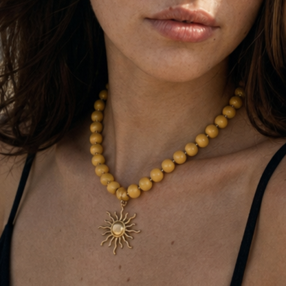 Model draagt een botergele kralenketting met goudkleurige statement zon bedel van Casa Jadel