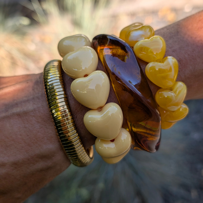 arm met botergele chubby hartjes armband gedraaide amber bangle en gouden armband