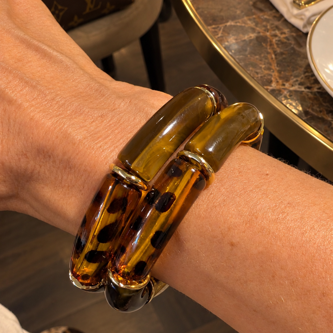 Bruine amber turtoise chunky tube armband met grote gebogen donkerbruine en amberkleurige kralen, panterprint en gouden tussenringen op een arm