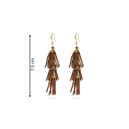 Bruine statement tassel oorbellen met lange gelaagde franjes van chocoladebruine glanzende staafkralen, gouden details en goudkleurige oorhaakjes op witte achtergrond afeting.
