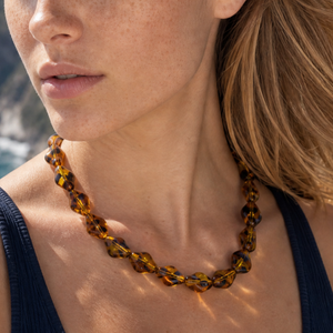 Model draagt een bruine transparante kralenketting met facet kralen in amberkleur van Casa Jadel