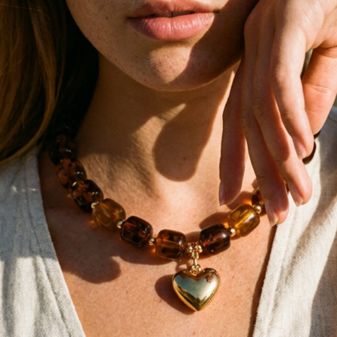 Model draagt een amberbruine transparante kralenketting met goudkleurige hart bedel van Casa Jadel