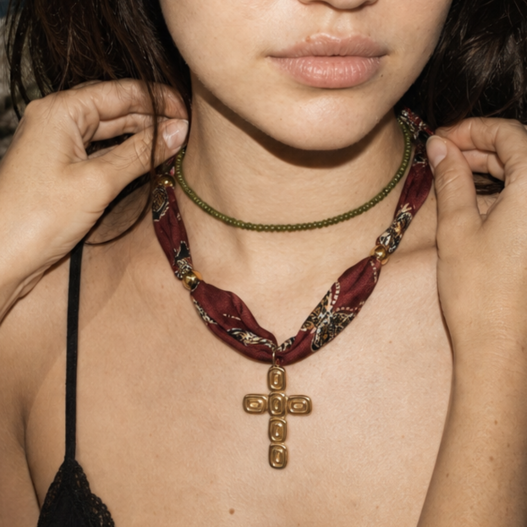 Model draagt een burgundy bandana ketting met goudkleurige kruis bedel en groene kleine kralenketting van Casa Jadel