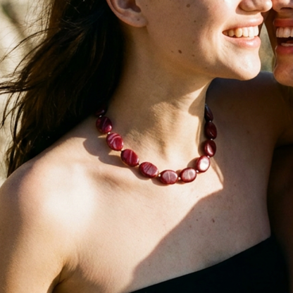 Model draagt een burgundy ovale kralenketting met goudkleurige tussenkralen van Casa Jadel