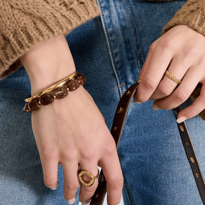 Model draagt amberkleurige square kralenarmband gecombineerd met gouden armband