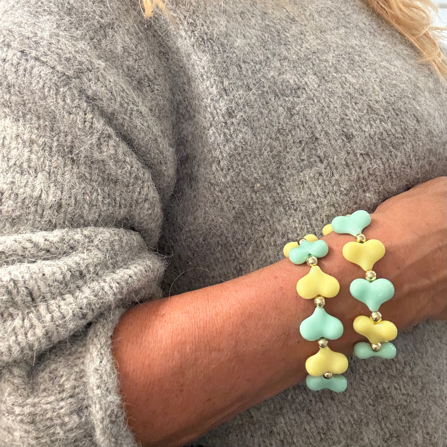 Close-up van lichtgroene en gele hartjesarmband gedragen om de pols
