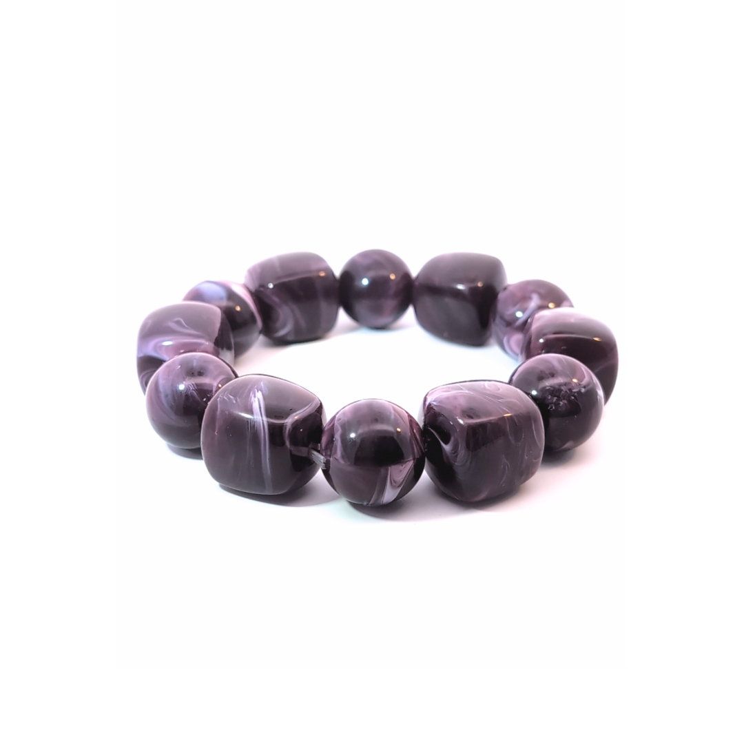 Grote kralenarmband in aubergine en paars met gemarmerde kralen, chunky Ibiza style armband schuin gefotografeerd op witte achtergrond.