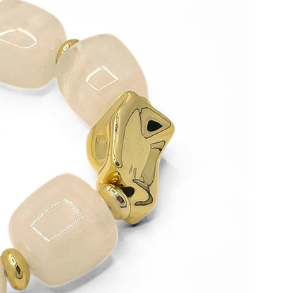 Detail van witte kralenarmband met marmer effect en gouden accentkraal unieke structuur kralen