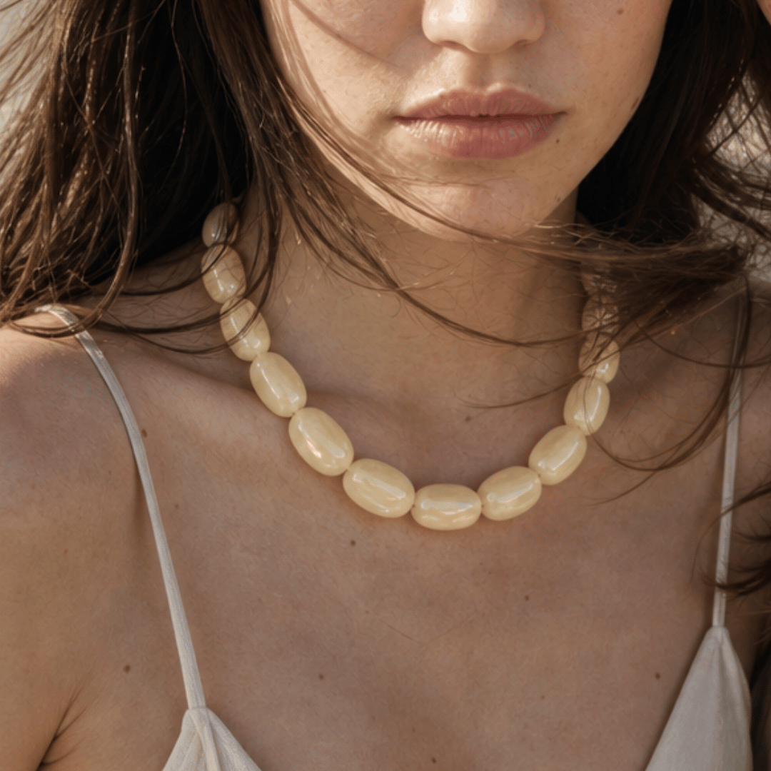 Model draagt crème oversized kralenketting van Casa Jadel