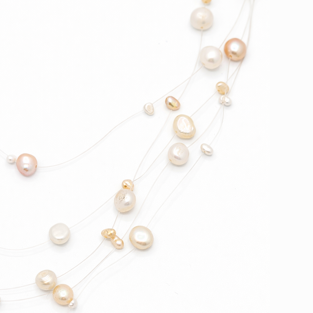 Detail van beige kralen aan transparante draad met floating effect in minimalistische parelketting