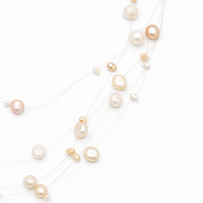 Detail van beige kralen aan transparante draad met floating effect in minimalistische parelketting