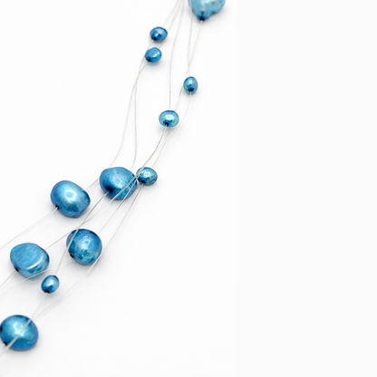 Detail van blauwe kralen aan transparante draad met floating effect in minimalistische parelketting