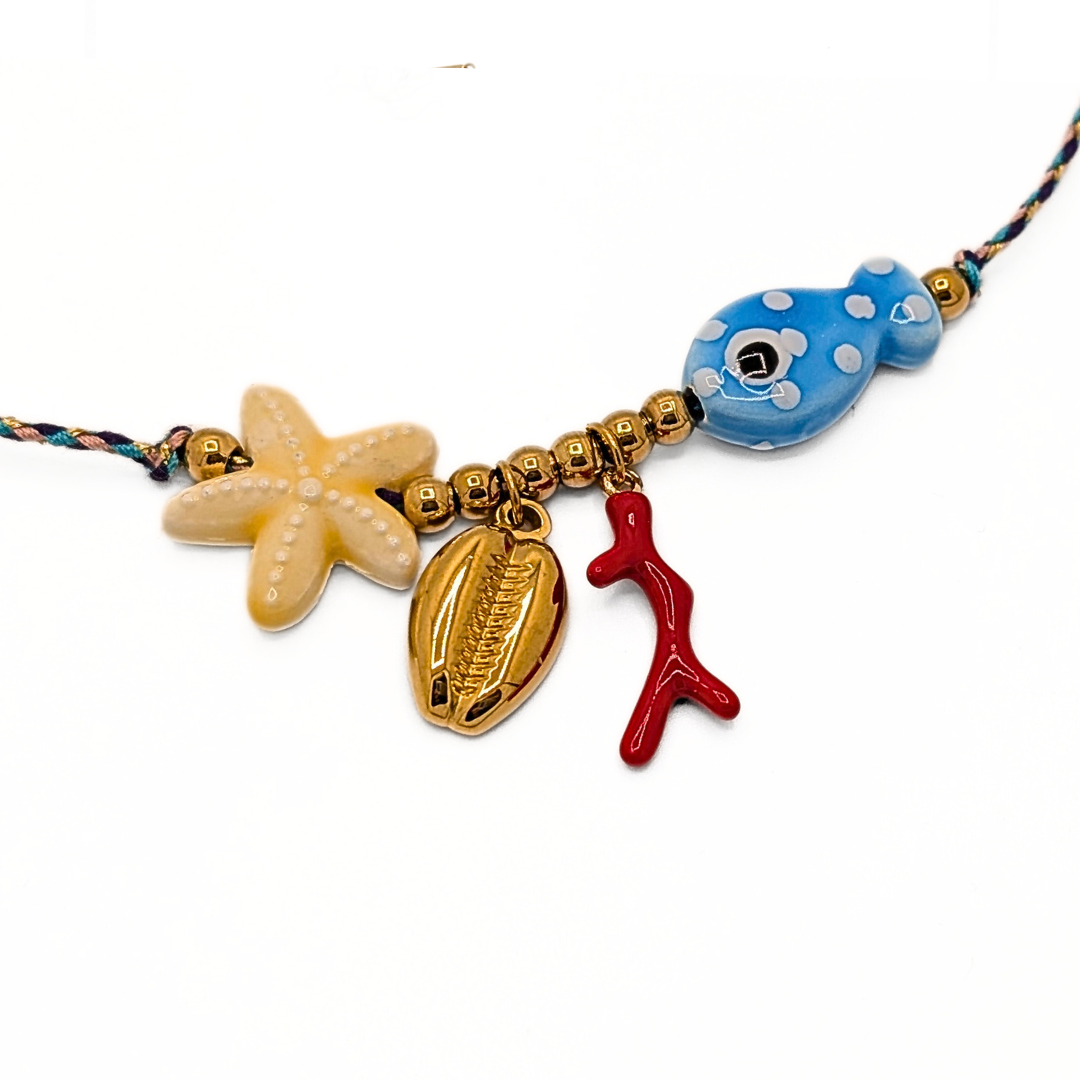 Detail van blauwe rope ketting met gouden kralen en zee bedels zoals zeester schelp vis en rood koraal van Casa Jadel