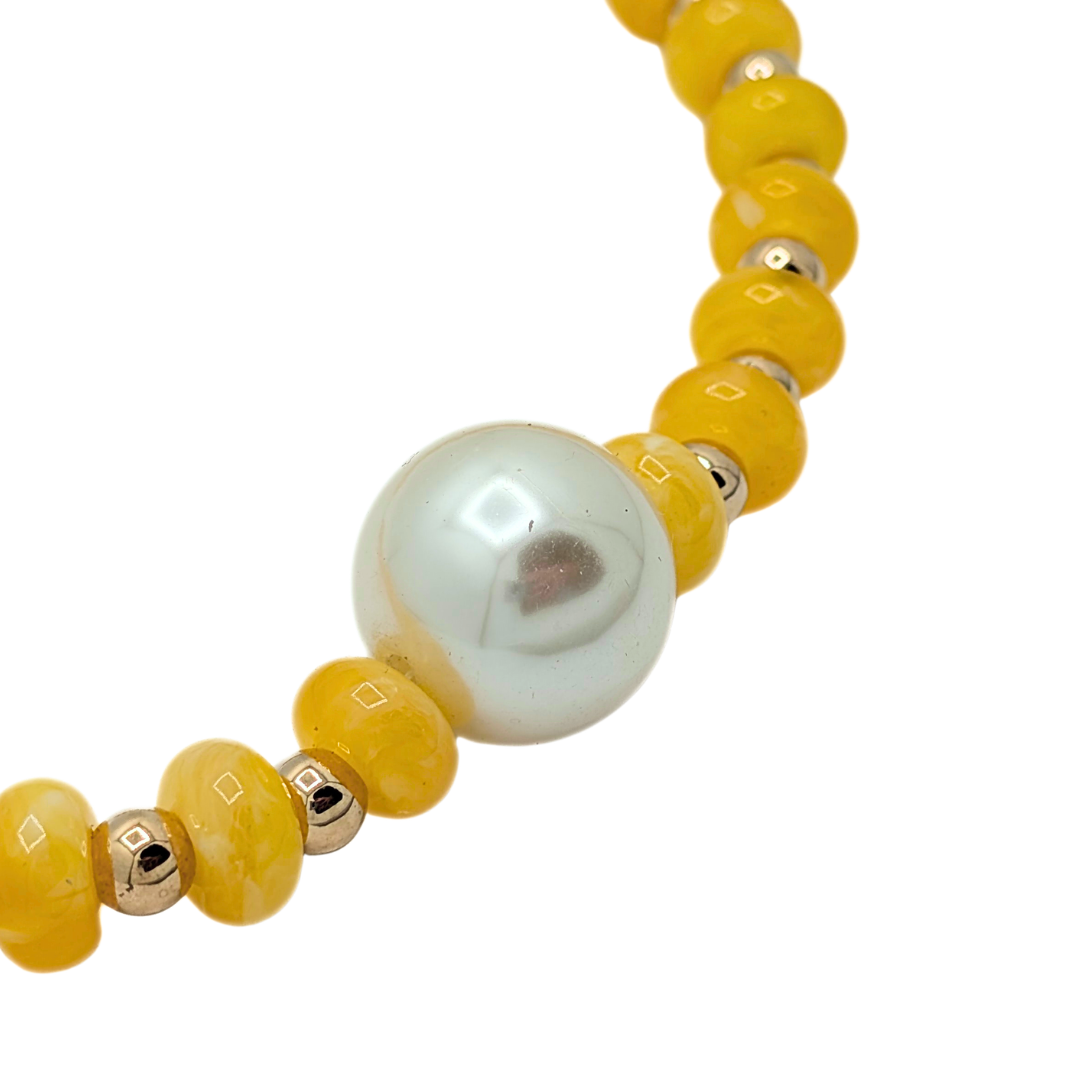 Detail van gele kralenketting met centrale parel
