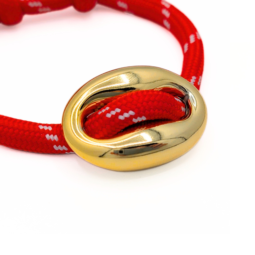 Detail van gouden bean op rode rope armband
