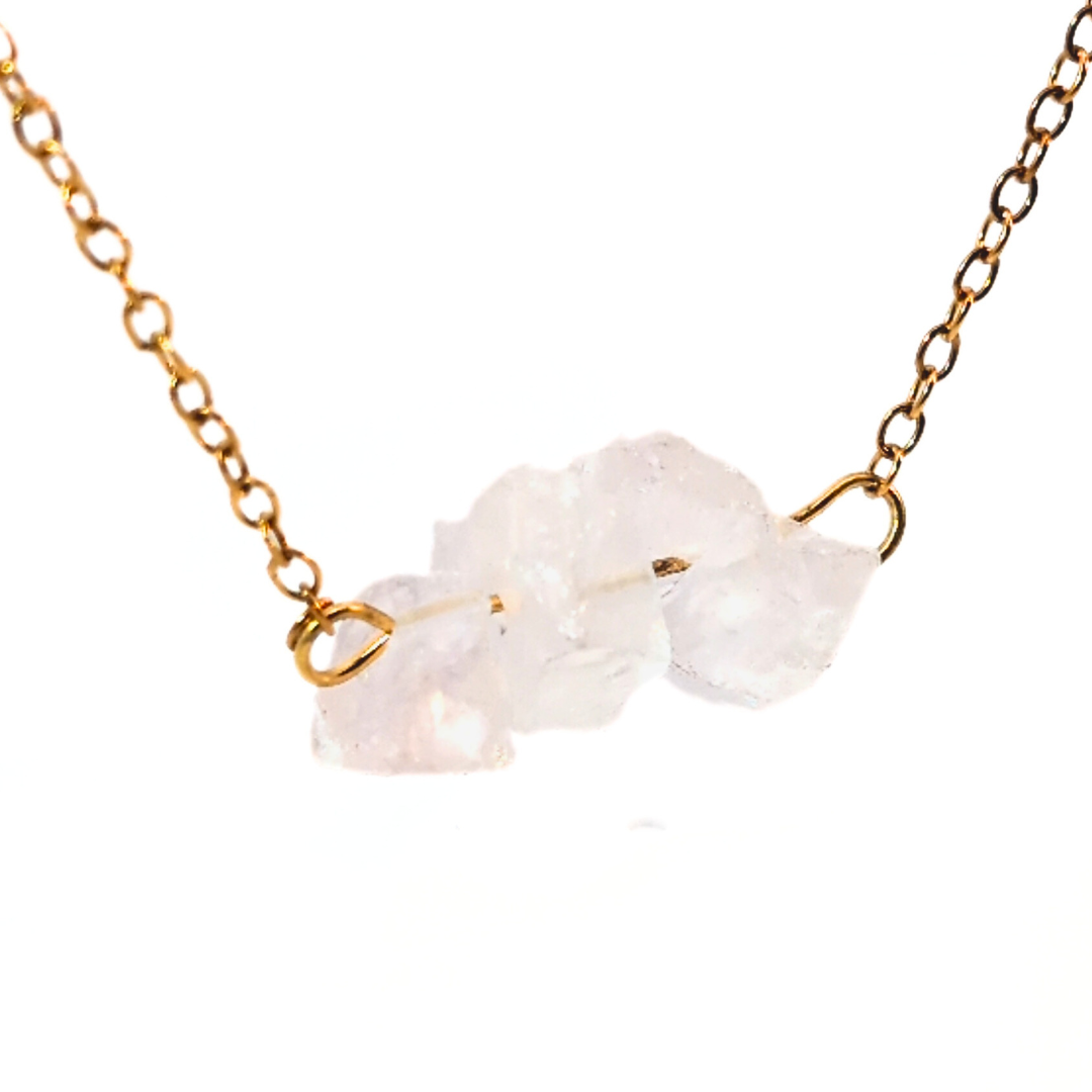 Detail van gouden ketting met drie natuurlijke bergkristal edelstenen