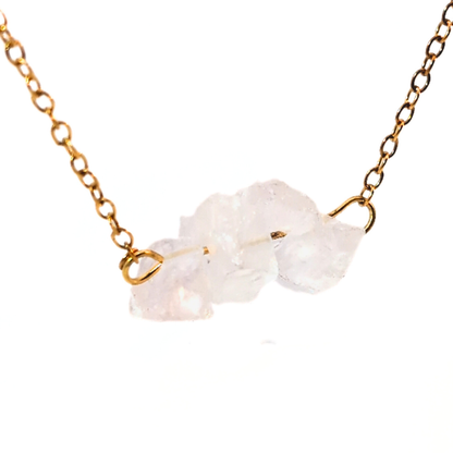 Detail van gouden ketting met drie natuurlijke bergkristal edelstenen