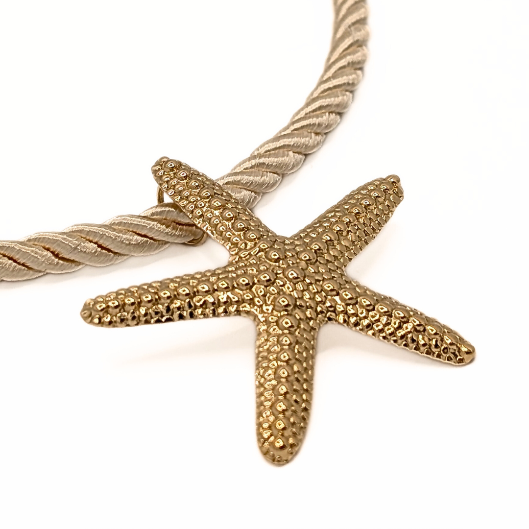 Detail van grote gouden zeester bedel aan naturel rope ketting