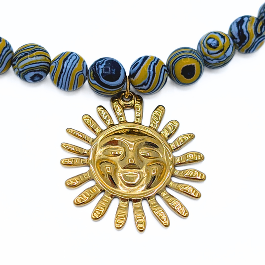 Detail van goudkleurige zon bedel aan blauwe kralen
