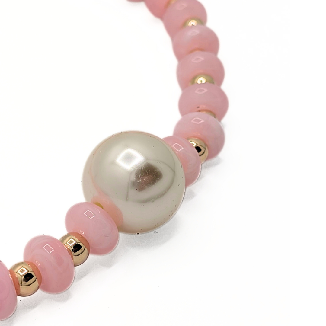Detail van grote parel aan roze kralenketting
