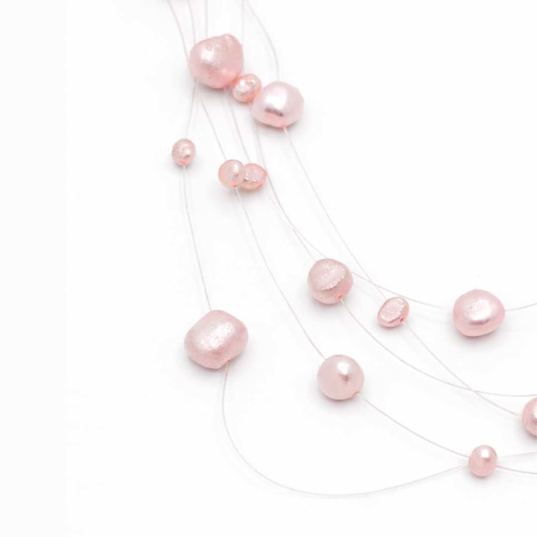 Detail van lichtroze kralen aan transparante draad met floating effect in minimalistische parelketting