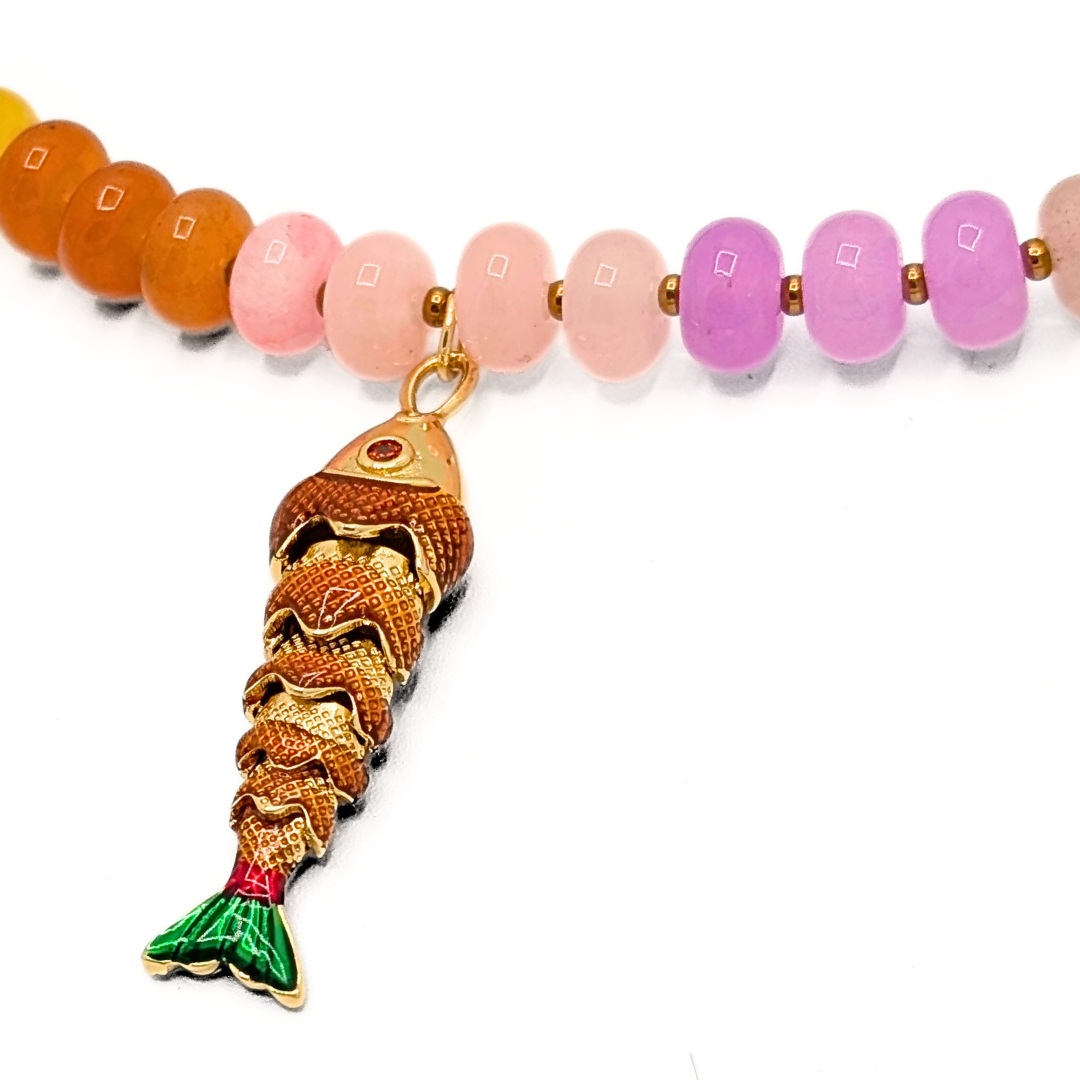 Detail van goudkleurige vis bedel aan kleurrijke kralenketting
