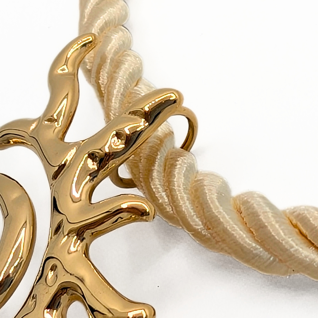 Detail van rope ketting in naturel kleur met gouden zon hanger en sluiting