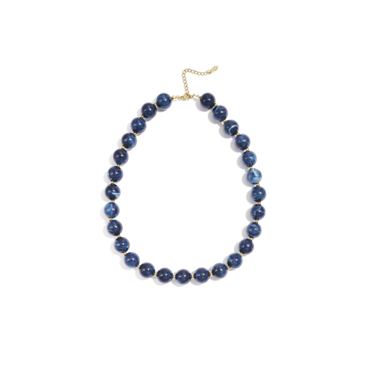 Donkerblauwe gemarmerde kralenketting met goudkleurige accenten op lichte achtergrond.