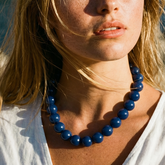 Model draagt grote kralenketting in het donkerblauw