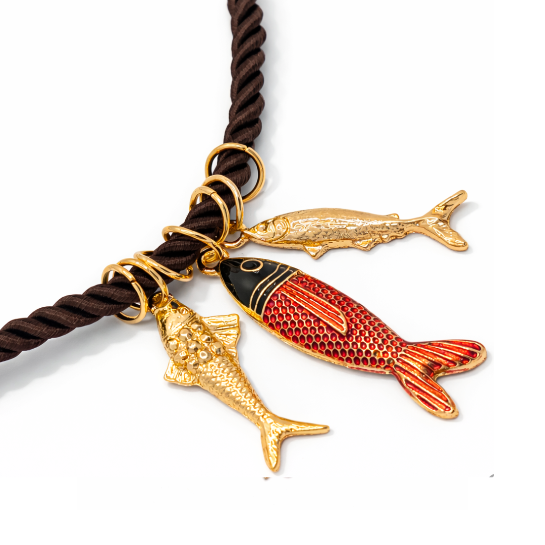 inzoom donkerbruine rope ketting met goudkleurige vis bedels en rood zwarte vis hanger.