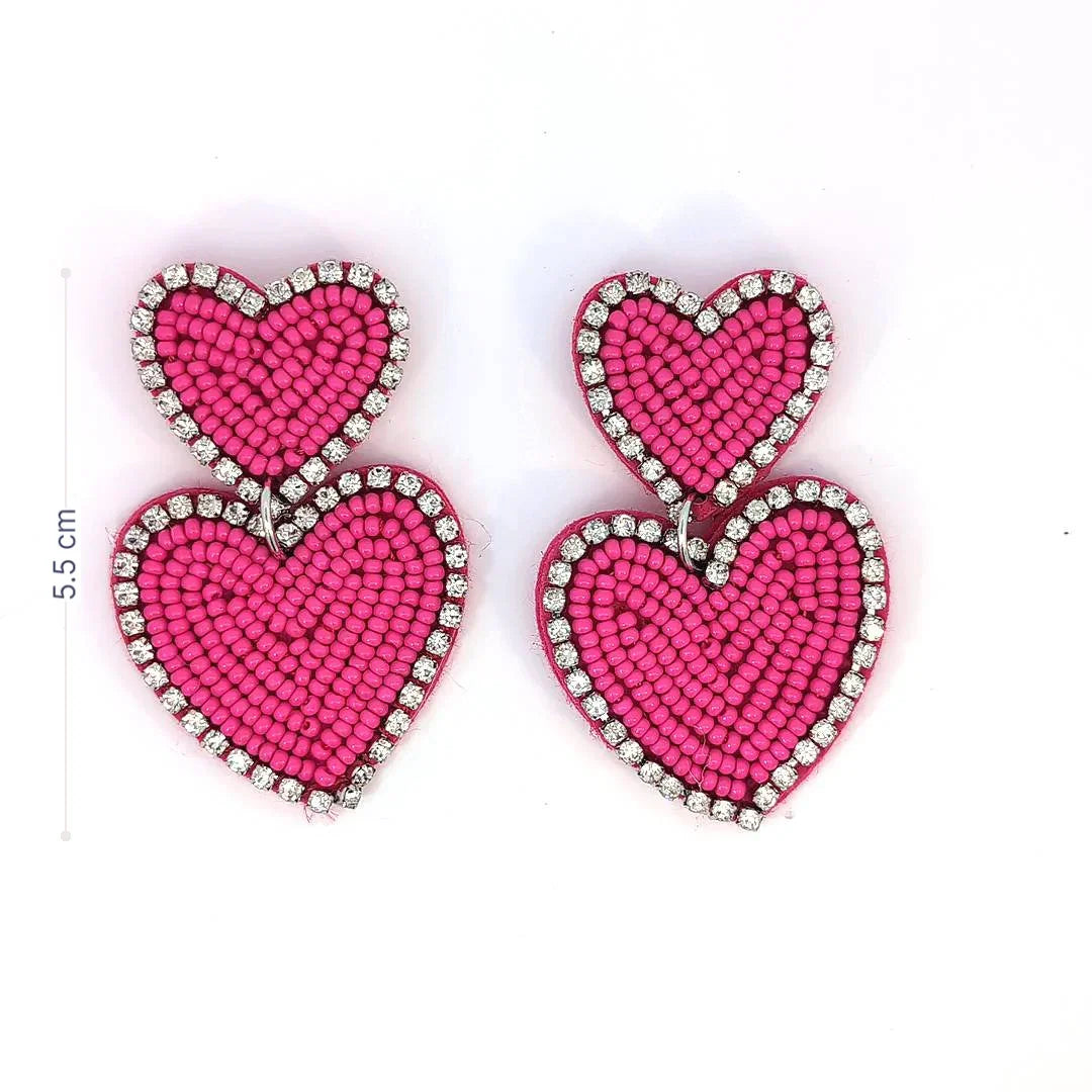 Felroze dubbele hart oorbellen met kraaltjes en strassrand op lichte achtergrond met afmeting