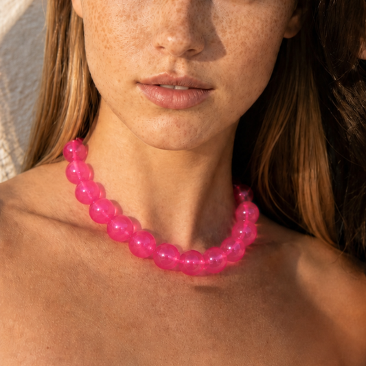 Model draagt een fuchsia transparante kralenketting met grote ronde kralen van Casa Jadel
