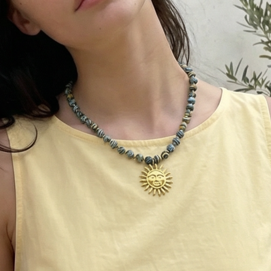 Model draag geel-blauwe planeten kralenketting met gouden zon hanger.