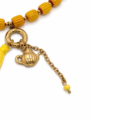 inzoom Geel oranjeglazen kralenketting dames met gouden theepot bedel en kleurrijk kwastje Ibiza stijl