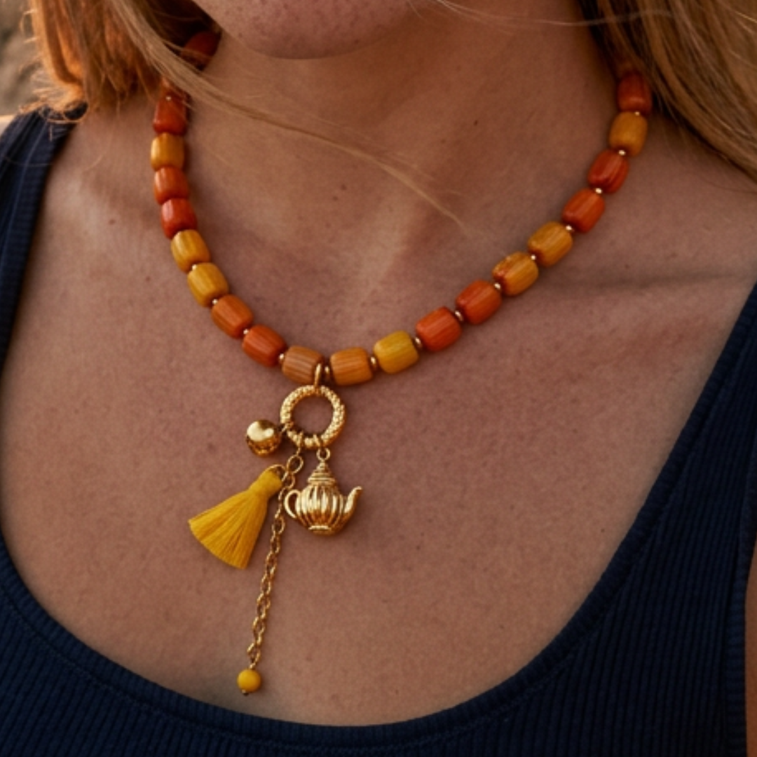 model met Geel oranjeglazen kralenketting dames met gouden theepot bedel en kleurrijk kwastje Ibiza stijl